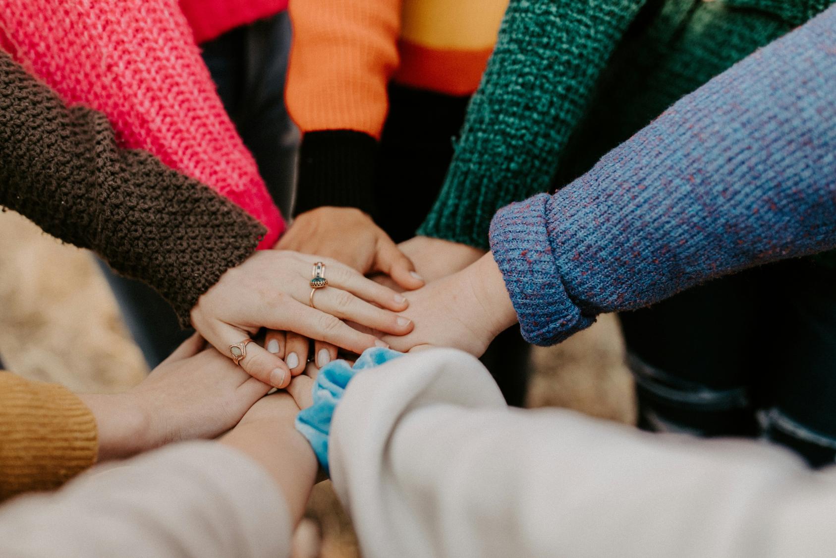people putting their hands together in a circle