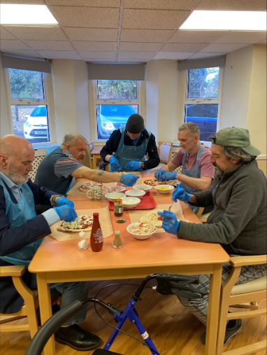 A group of residents enjoying making pizza together